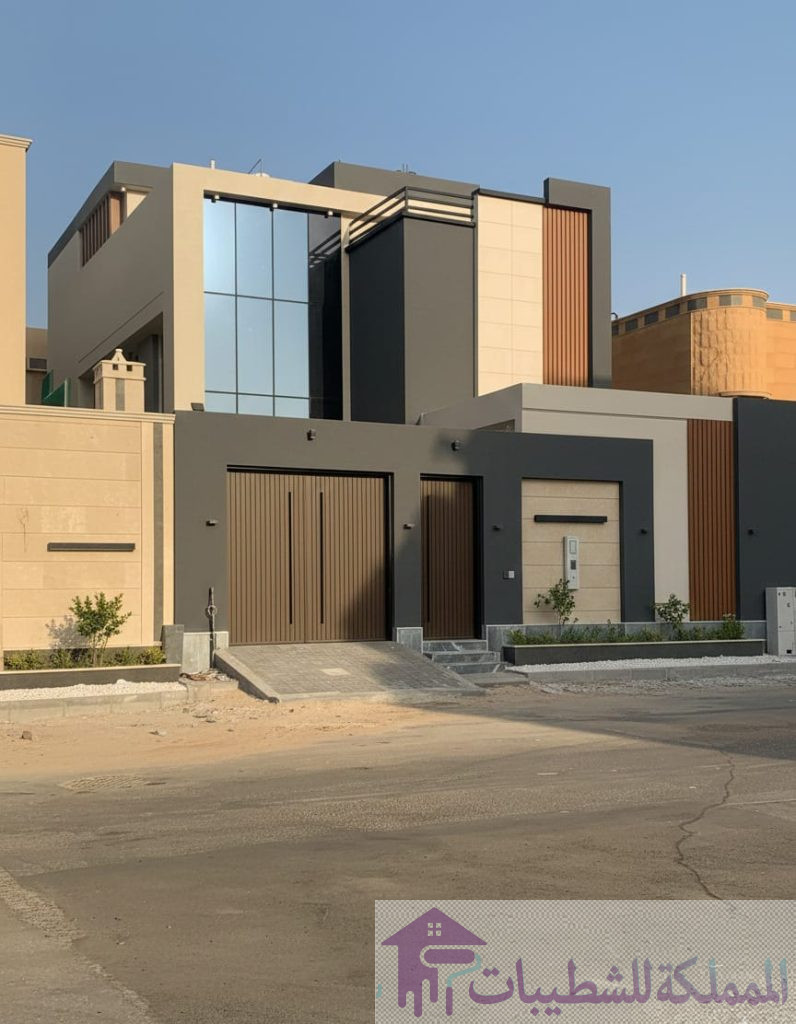 "تصميم وتنفيذ واجهة فيلا مودرن في حي العزيزية بالدمام، تدمج بين دهانات البروفايل الرمادي الغامق (الفحمي) وتكسيات بديل الخشب الطولية."